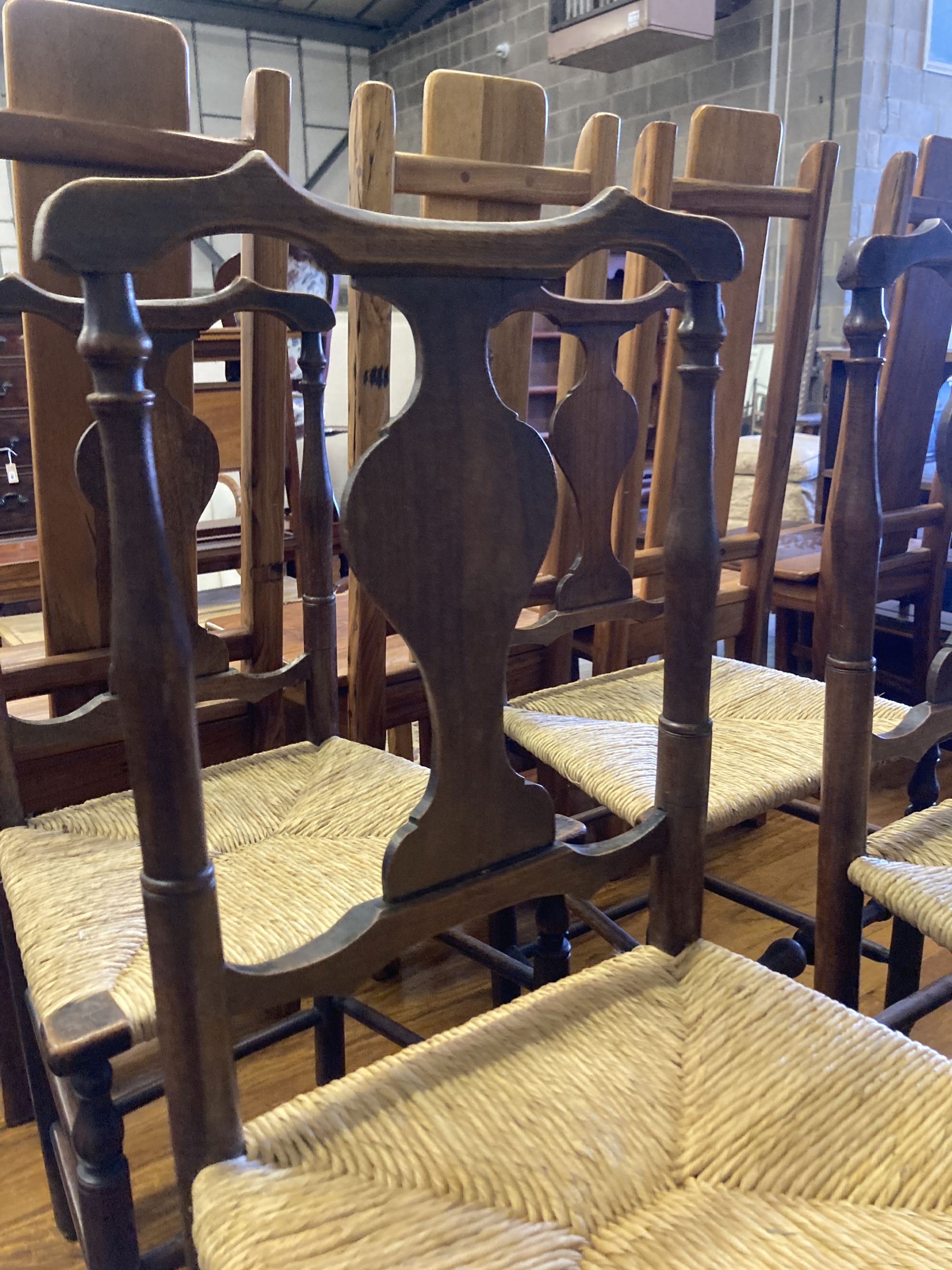 A set of four George III country oak rush seated chairs, with shaped back splat, turned supports and stretchers